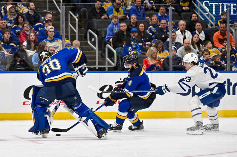 Feb 19, 2024; St. Louis, Missouri, USA;  St. Louis Blues goaltender Joel Hofer (30) and defenseman Nick Leddy (4) controls the puck against Toronto Maple Leafs left wing Matthew Knies (23) during the third period at Enterprise Center. Mandatory Credit: Jeff Curry-USA TODAY Sports