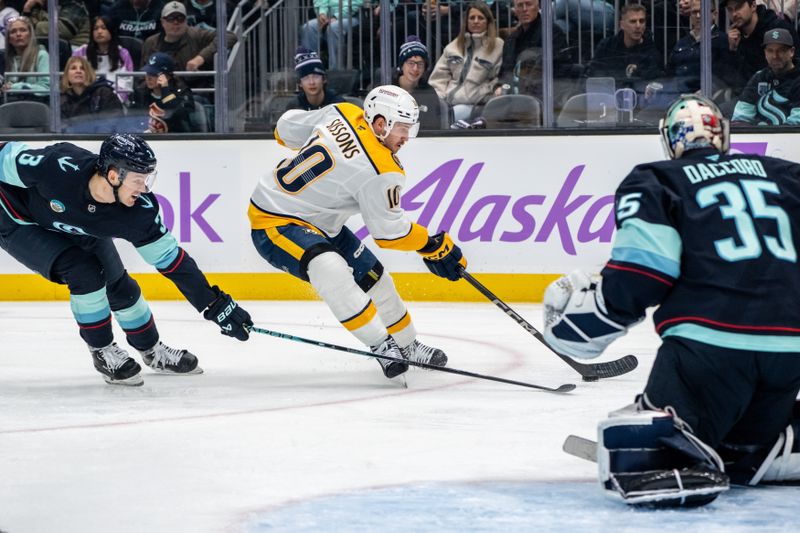 Nov 20, 2024; Seattle, Washington, USA;  Nashville Predators forward Colton Sissons (10) skates against Seattle Kraken defenseman Will Borgen (3) and goalie Joey Daccord (35) during the first period at Climate Pledge Arena. Mandatory Credit: Stephen Brashear-Imagn Images