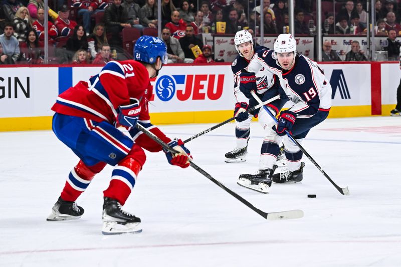 Nov 16, 2024; Montreal, Quebec, CAN; Columbus Blue Jackets center Adam Fantilli (19) plays the puck against Montreal Canadiens defenseman Kaiden Guhle (21)  during the third period at Bell Centre. Mandatory Credit: David Kirouac-Imagn Images