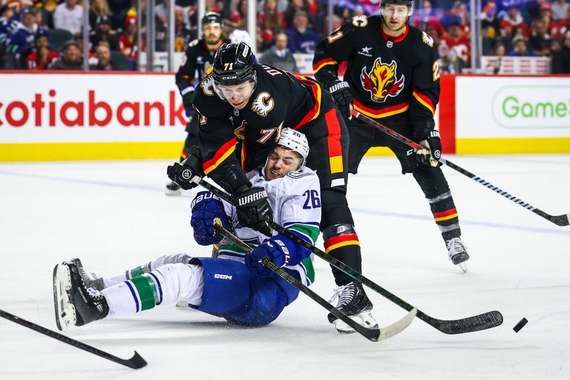 Dec 31, 2024; Calgary, Alberta, CAN; Vancouver Canucks defenseman Erik Brannstrom (26) and Calgary Flames right wing Walker Duehr (71) battles for the puck during the third period at Scotiabank Saddledome. Mandatory Credit: Sergei Belski-Imagn Images