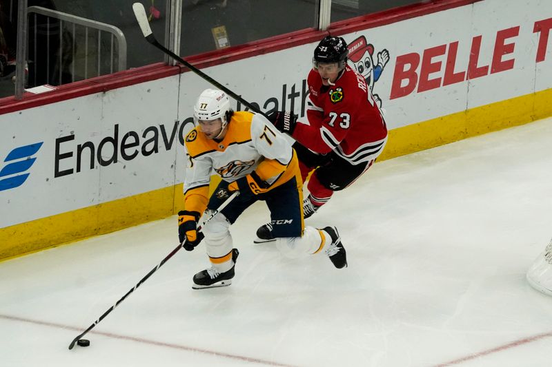 Oct 25, 2024; Chicago, Illinois, USA; Chicago Blackhawks left wing Lukas Reichel (73) defends Nashville Predators right wing Luke Evangelista (77) during the third period at the United Center. Mandatory Credit: David Banks-Imagn Images