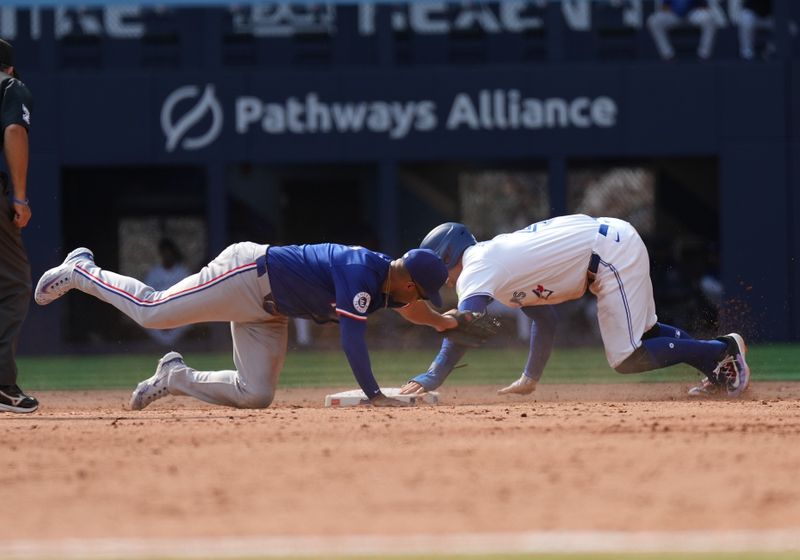 Jul 27, 2024; Toronto, Ontario, CAN; Toronto Blue Jays right fielder George Springer (4) steals second base ahead of the tag from Texas Rangers shortstop Corey Seager (5) during the sixth inning at Rogers Centre. Mandatory Credit: Nick Turchiaro-USA TODAY Sports