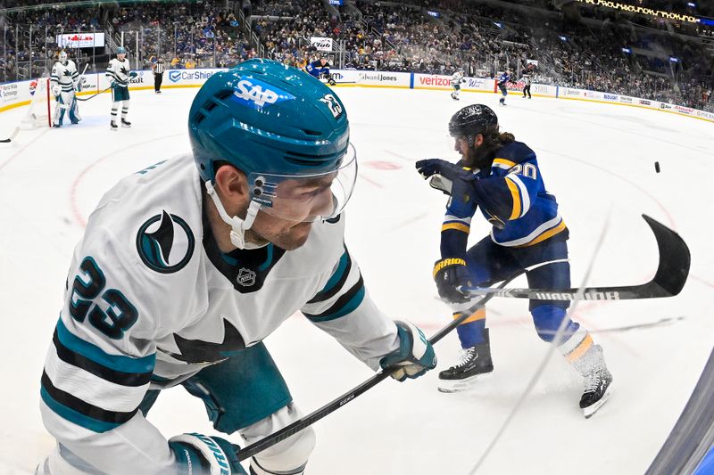 Nov 21, 2024; St. Louis, Missouri, USA;  San Jose Sharks right wing Barclay Goodrow (23) clears the puck past St. Louis Blues left wing Brandon Saad (20) during the second period at Enterprise Center. Mandatory Credit: Jeff Curry-Imagn Images