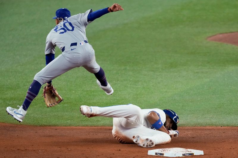 Oct 24, 2025; Toronto, Ontario, CAN; Toronto Blue Jays first baseman Vladimir Guerrero Jr. (27) is out at second base as Los Angeles Dodgers shortstop Mookie Betts (50) turns a double play in the third inning during game one of the 2025 MLB World Series at Rogers Centre. Mandatory Credit: Kevin Sousa-Imagn Images