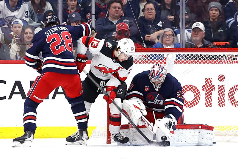 Apr 2, 2023; Winnipeg, Manitoba, CAN; Winnipeg Jets goaltender Connor Hellebuyck (37) blocks a shot by New Jersey Devils center Nico Hischier (13) in the second period at Canada Life Centre. Mandatory Credit: James Carey Lauder-USA TODAY Sports