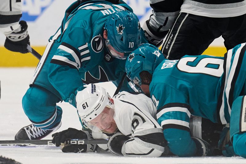 Apr 4, 2024; San Jose, California, USA; Los Angeles Kings center Trevor Lewis (61) vies for the puck against San Jose Sharks center Luke Kunin (11) and center Mikael Granlund (64) during the third period at SAP Center at San Jose. Mandatory Credit: Robert Edwards-USA TODAY Sports