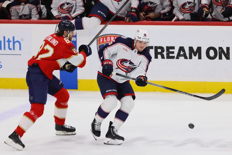 Apr 11, 2024; Sunrise, Florida, USA; Columbus Blue Jackets center Brendan Gaunce (16) passes the puck as Florida Panthers center Kevin Stenlund (82) defends during the first period at Amerant Bank Arena. Mandatory Credit: Sam Navarro-USA TODAY Sports