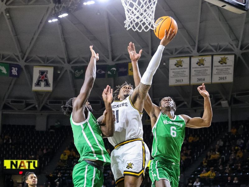 Jan 29, 2025; Wichita, Kansas, USA; Wichita State Shockers guard Justin Hill (11) shoots the ball around North Texas Mean Green forward Brenen Lorient (6) during the second half at Charles Koch Arena. Mandatory Credit: William Purnell-Imagn Images