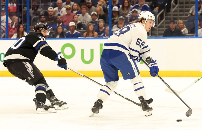 Apr 17, 2024; Tampa, Florida, USA; Toronto Maple Leafs left wing Tyler Bertuzzi (59) skates with the puck as Tampa Bay Lightning left wing Nicholas Paul (20) defends during the first period at Amalie Arena. Mandatory Credit: Kim Klement Neitzel-USA TODAY Sports