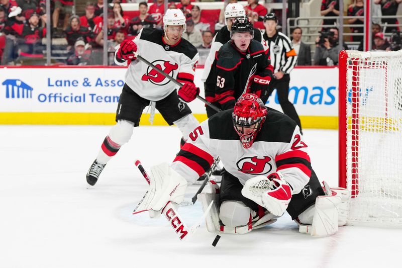 Apr 20, 2025; Raleigh, North Carolina, USA; New Jersey Devils goaltender Jacob Markstrom (25) reaches for the puck against the Carolina Hurricanes during the first period of game one of the first round of the 2025 Stanley Cup Playoffs at Lenovo Center. Mandatory Credit: James Guillory-Imagn Images