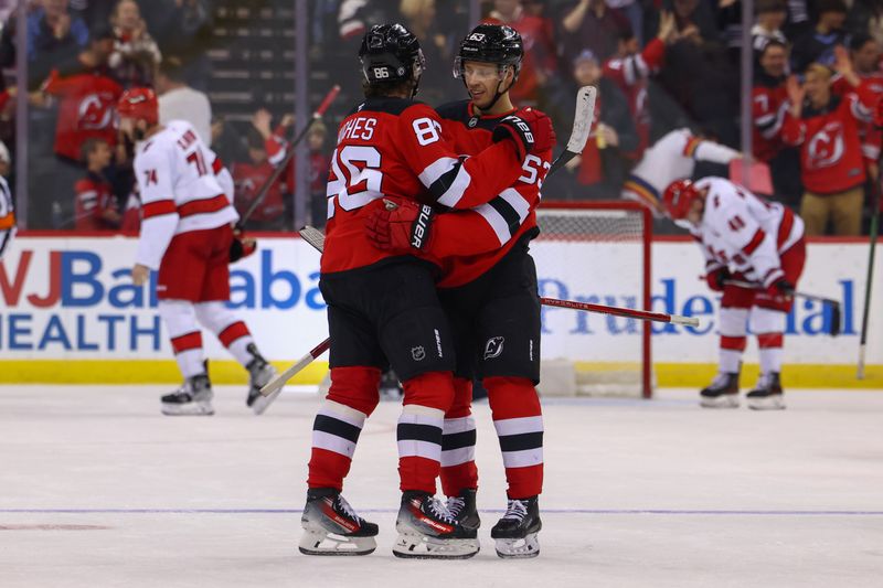 Nov 21, 2024; Newark, New Jersey, USA; New Jersey Devils left wing Jesper Bratt (63) and center Jack Hughes (86) celebrate Bratt’s goal against the Carolina Hurricanes during the third period at Prudential Center. Mandatory Credit: Ed Mulholland-Imagn Images