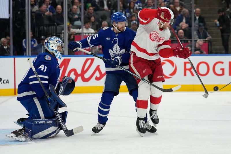 Nov 8, 2024; Toronto, Ontario, CAN; Detroit Red Wings forward Andrew Copp (18) tries to deflect a puck as Toronto Maple Leafs goaltender Anthony Stolarz (41) and defenceman Oliver Ekman-Larsson (95) defend during the second period at Scotiabank Arena. Mandatory Credit: John E. Sokolowski-Imagn Images