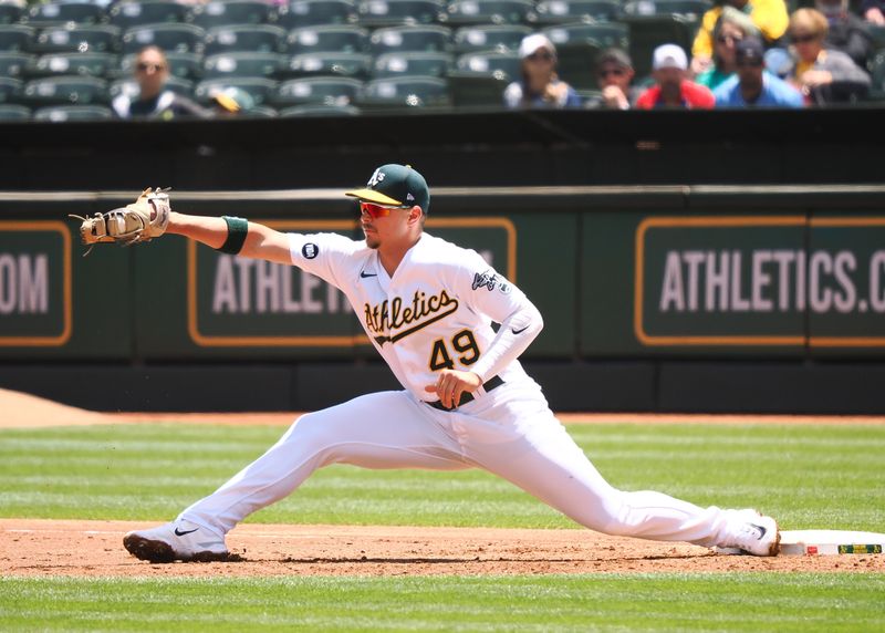 May 31, 2023; Oakland, California, USA; Oakland Athletics first baseman Ryan Noda (49) reaches for the ball against the Atlanta Braves during the third inning at Oakland-Alameda County Coliseum. Mandatory Credit: Kelley L Cox-USA TODAY Sports