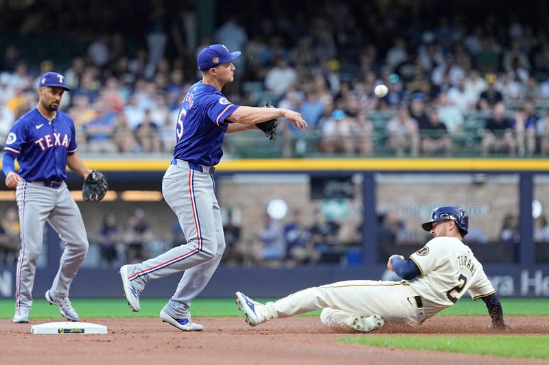 Jun 24, 2024; Milwaukee, Wisconsin, USA;  Texas Rangers shortstop Corey Seager (5) turns a double playa as Milwaukee Brewers second baseman Brice Turing (2) slides into second base during the first inning at American Family Field. Mandatory Credit: Jeff Hanisch-USA TODAY Sports