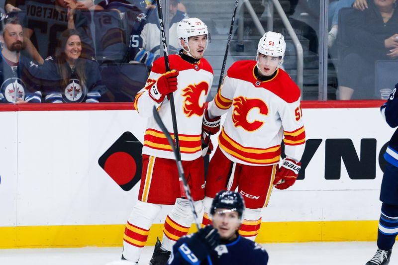 Sep 27, 2025; Winnipeg, Manitoba, CAN;  Calgary Flames defenseman Yan Kuznetsov (37) is congratulated by forward Matvel Gridin (51) on his goal against the Winnipeg Jets during the third period at Canada Life Centre. Mandatory Credit: Terrence Lee-Imagn Images
