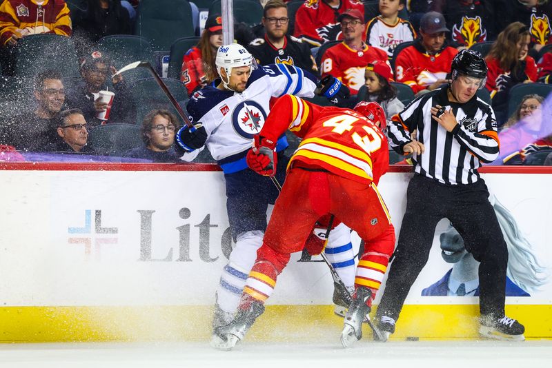 Oct 4, 2024; Calgary, Alberta, CAN; Calgary Flames right wing Adam Klapka (43) and Winnipeg Jets right wing Nino Niederreiter (62) battles for the puck during the third period at Scotiabank Saddledome. Mandatory Credit: Sergei Belski-Imagn Images