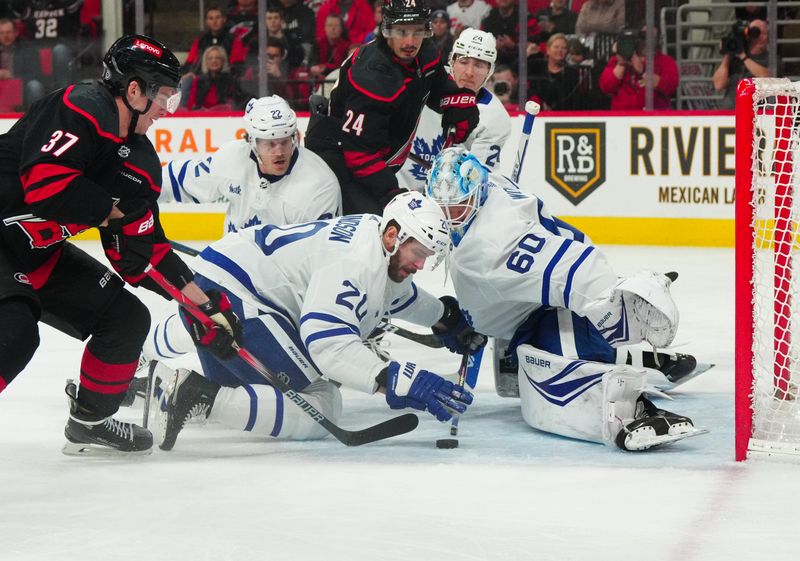 Mar 24, 2024; Raleigh, North Carolina, USA;  Toronto Maple Leafs defenseman Joel Edmundson (20) covers the puck with his glove for a penalty against the Carolina Hurricanes during the first period at PNC Arena. Mandatory Credit: James Guillory-USA TODAY Sports