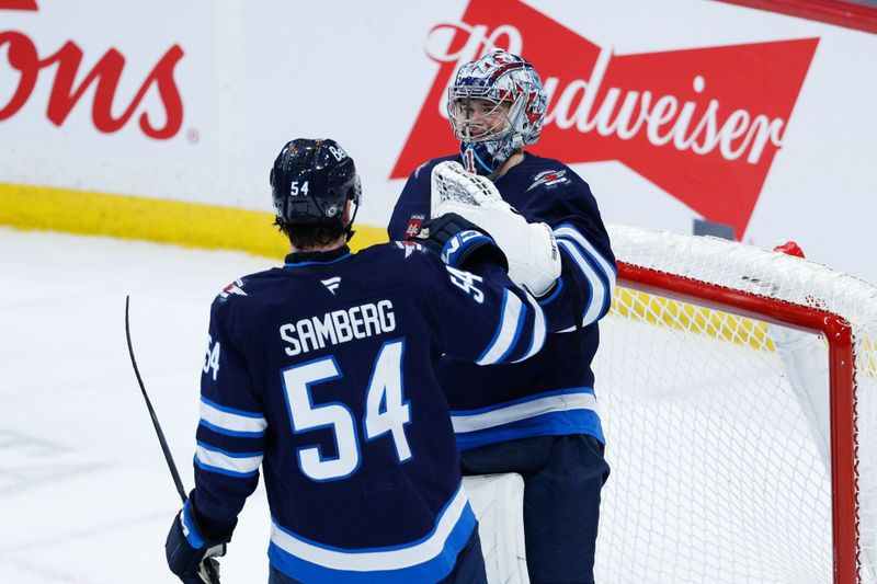 Jan 26, 2025; Winnipeg, Manitoba, CAN;  Winnipeg Jets goalie Eric Comrie (1) is congratulated by Winnipeg Jets defenseman Hayden Fleury (24) on his win against the Calgary Flames at the end of the third period at Canada Life Centre. Mandatory Credit: Terrence Lee-Imagn Images