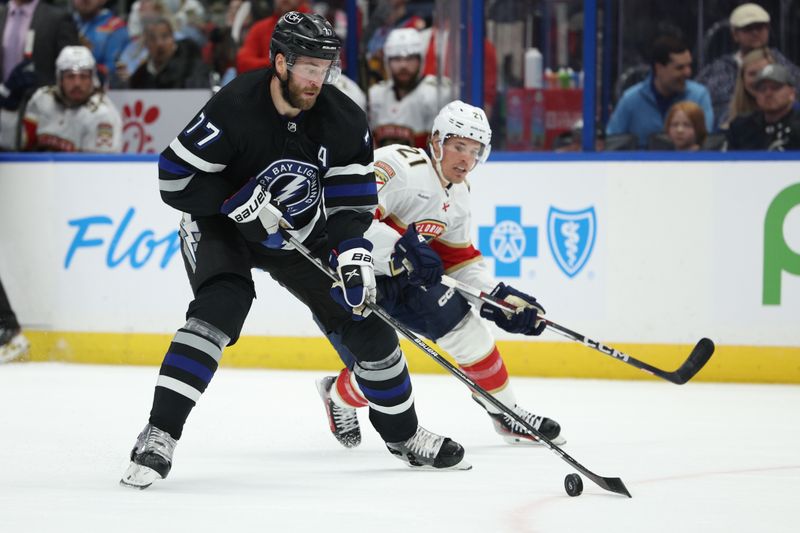 Feb 17, 2024; Tampa, Florida, USA;  Tampa Bay Lightning defenseman Victor Hedman (77) controls the puck  from Florida Panthers center Nick Cousins (21) in the second period at Amalie Arena. Mandatory Credit: Nathan Ray Seebeck-USA TODAY Sports