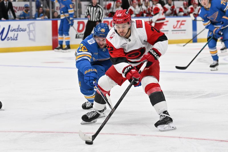 Jan 13, 2026; St. Louis, Missouri, USA; St. Louis Blues left wing Nathan Walker (26) battles Carolina Hurricanes center Logan Stankoven (22) for the puck in the third period at Enterprise Center. Mandatory Credit: Joe Puetz-Imagn Images