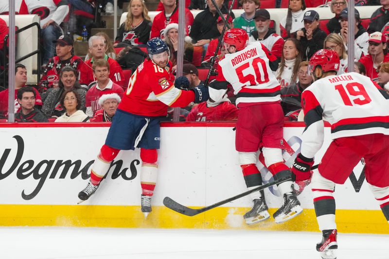 Dec 23, 2025; Raleigh, North Carolina, USA;  Carolina Hurricanes left wing Eric Robinson (50) checks Florida Panthers left wing Noah Gregor (18) during the second period at Lenovo Center. Mandatory Credit: James Guillory-Imagn Images