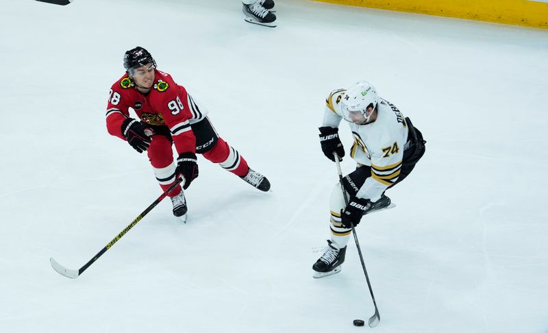 Oct 24, 2023; Chicago, Illinois, USA; Chicago Blackhawks center Connor Bedard (98) defends Boston Bruins left wing Jake DeBrusk (74) during the second period at United Center. Mandatory Credit: David Banks-USA TODAY Sports