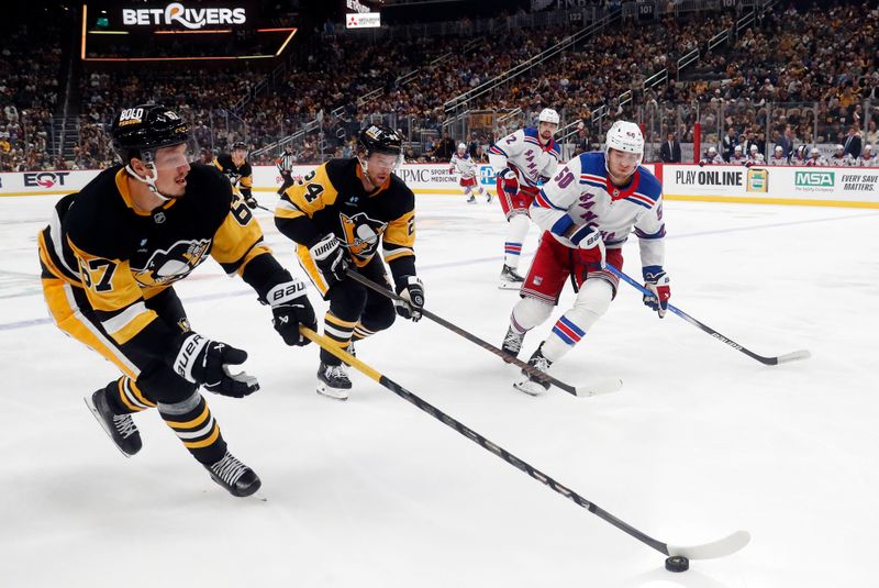 Oct 9, 2024; Pittsburgh, Pennsylvania, USA;  Pittsburgh Penguins right wing Rickard Rakell (67) reaches for a loose puck against the New York Rangers during the second period at PPG Paints Arena. Mandatory Credit: Charles LeClaire-Imagn Images