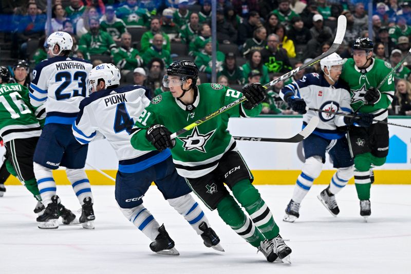 Feb 29, 2024; Dallas, Texas, USA; Winnipeg Jets defenseman Neal Pionk (4) and Dallas Stars left wing Jason Robertson (21) look for the puck in the Jets zone during the second period at the American Airlines Center. Mandatory Credit: Jerome Miron-USA TODAY Sports