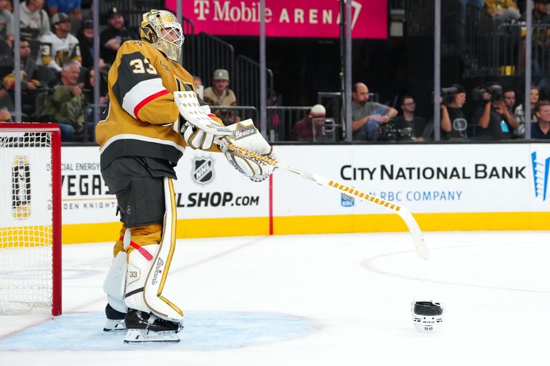 Sep 27, 2024; Las Vegas, Nevada, USA; Vegas Golden Knights goaltender Adin Hill (33) sends the helmet of Utah Hockey Club forward Logan Cooley (92) back towards the bench during the third period at T-Mobile Arena. Mandatory Credit: Stephen R. Sylvanie-Imagn Images