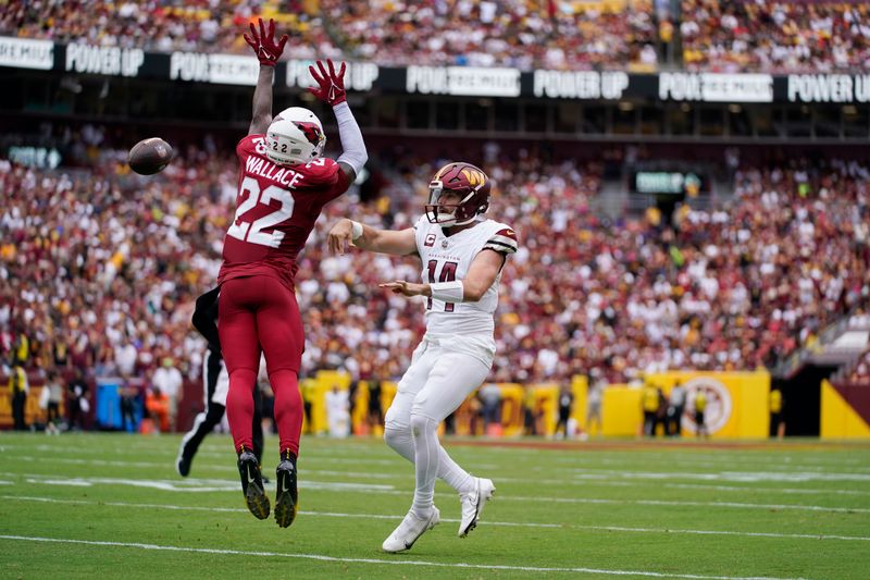 Washington Commanders quarterback Sam Howell (14) throws a touchdown pass around Arizona Cardinals safety K'Von Wallace (22) to Commanders running back Brian Robinson Jr. (8) during the first half of an NFL preseason football game, Sunday, Sept. 10, 2023, in Landover, Md. (AP Photo/Alex Brandon)