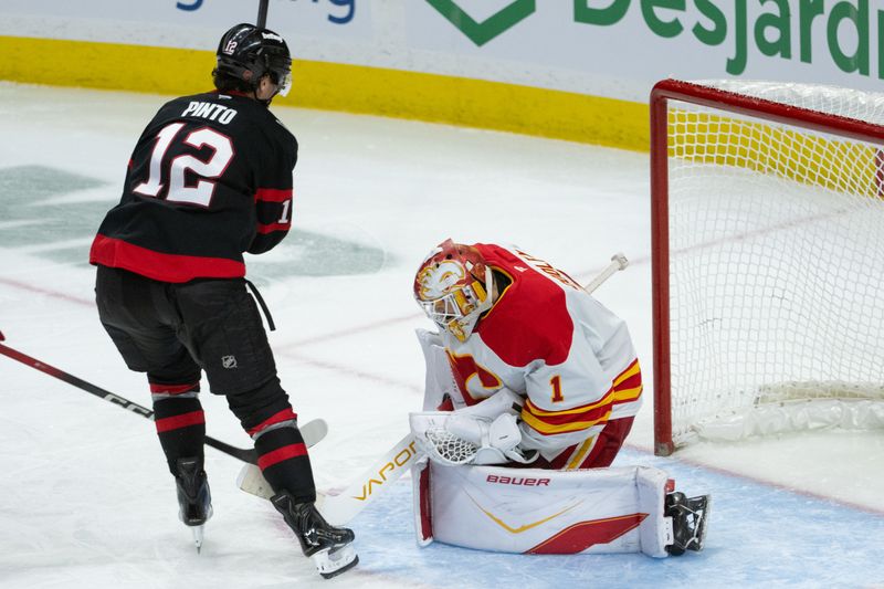 Oct 30, 2025; Ottawa, Ontario, CAN; Calgary Flames goalie Devin Cooley (1) makes a save in front of Ottawa Senators center Shane Pinto (12) in the third period at the Canadian Tire Centre. Mandatory Credit: Marc DesRosiers-IMAGN Images