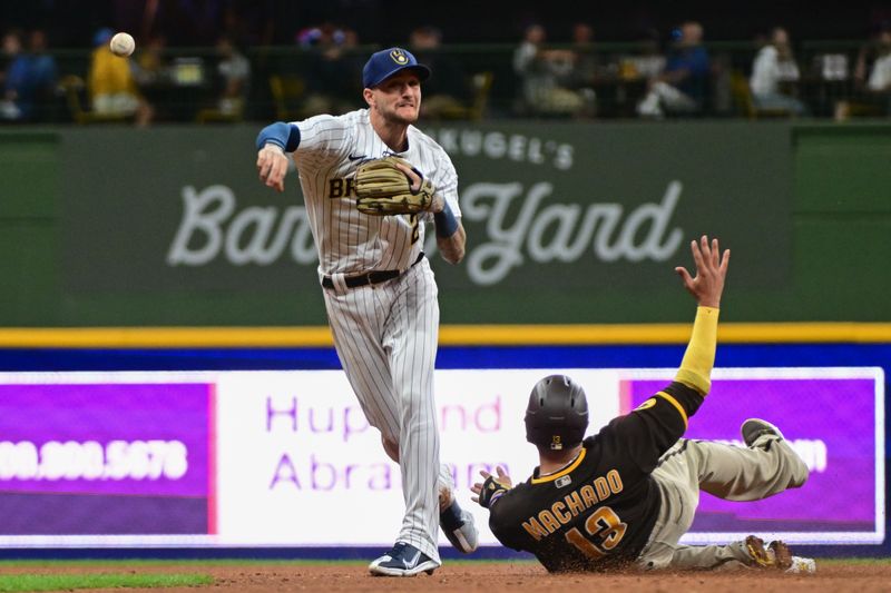 Aug 26, 2023; Milwaukee, Wisconsin, USA; Milwaukee Brewers second baseman Brice Turang (2) completes a double play after forcing out San Diego Padres third baseman Manny Machado (13) in the sixth inning at American Family Field. Mandatory Credit: Benny Sieu-USA TODAY Sports