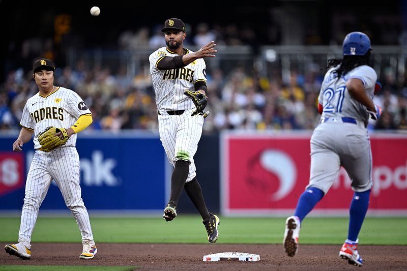 Apr 20, 2024; San Diego, California, USA; San Diego Padres second baseman Xander Bogaerts (center) throws to first base after forcing out Toronto Blue Jays first baseman Vladimir Guerrero Jr. (27) at second base to complete a double play as shortstop Ha-Seong Kim (7) looks on during the fifth inning at Petco Park. Mandatory Credit: Orlando Ramirez-USA TODAY Sports
