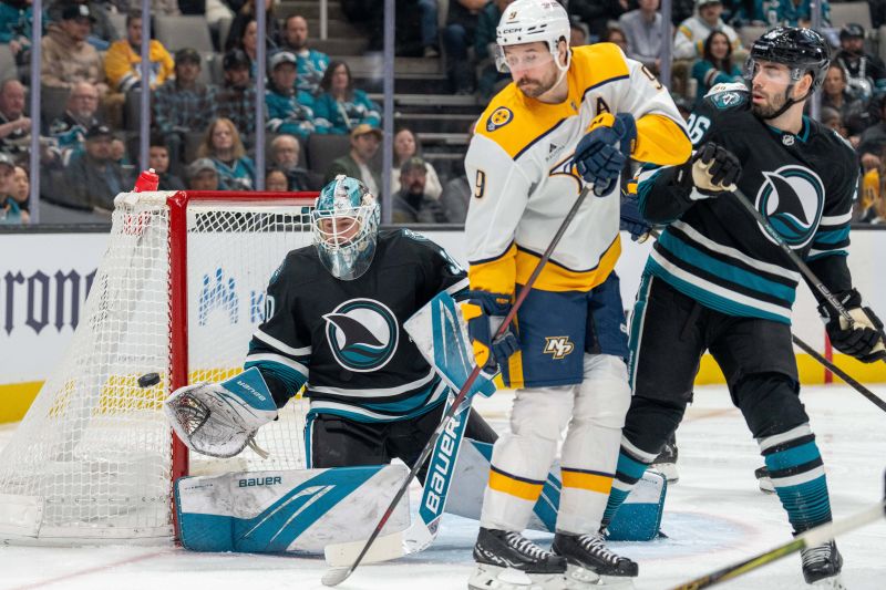 Jan 23, 2025; San Jose, California, USA;  San Jose Sharks goaltender Yaroslav Askarov (30) makes a save with Nashville Predators left wing Filip Forsberg (9) fights for position during the first period at SAP Center at San Jose. Mandatory Credit: Neville E. Guard-Imagn Images