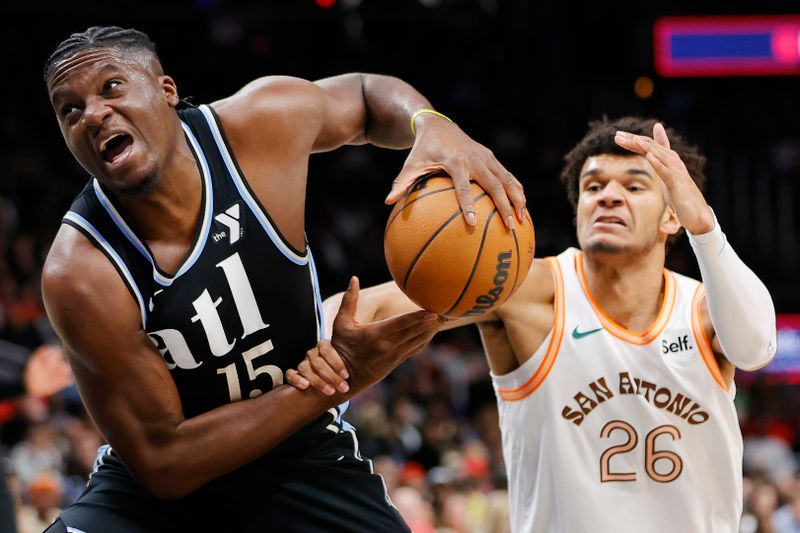 ATLANTA, GEORGIA - JANUARY 15: Clint Capela #15 of the Atlanta Hawks draws a foul from Dominick Barlow #26 of the San Antonio Spurs during the first half at State Farm Arena on January 15, 2024 in Atlanta, Georgia. NOTE TO USER: User expressly acknowledges and agrees that, by downloading and or using this photograph, User is consenting to the terms and conditions of the Getty Images License Agreement. (Photo by Alex Slitz/Getty Images)