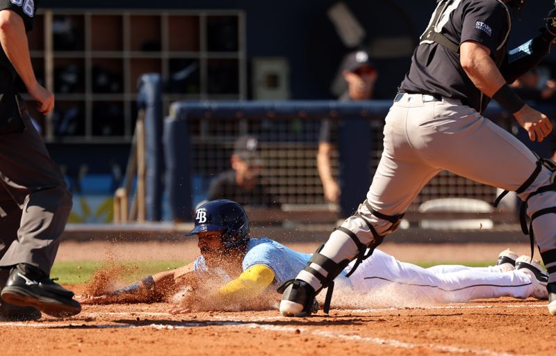 Feb 27, 2024; Port Charlotte, Florida, USA; Tampa Bay Rays second baseman Jose Caballero (7) slides safely into home plate during the fifth inning against the New York Yankees  at Charlotte Sports Park. Mandatory Credit: Kim Klement Neitzel-USA TODAY Sports