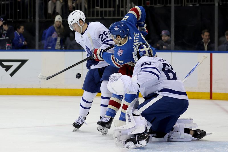 Mar 5, 2026; New York, New York, USA; New York Rangers left wing Tye Kartye (24) fights for the puck against Toronto Maple Leafs center Jacob Quillan (26) and goaltender Joseph Woll (60) during the second period at Madison Square Garden. Mandatory Credit: Brad Penner-Imagn Images