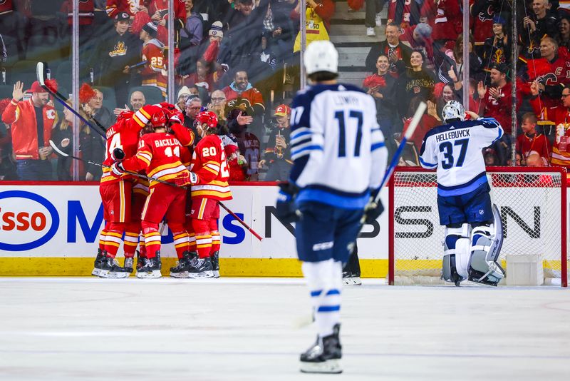 Feb 19, 2024; Calgary, Alberta, CAN; Calgary Flames defenseman Oliver Kylington (58) celebrates his goal with teammates against Winnipeg Jets goaltender Connor Hellebuyck (37) during the first period at Scotiabank Saddledome. Mandatory Credit: Sergei Belski-USA TODAY Sports