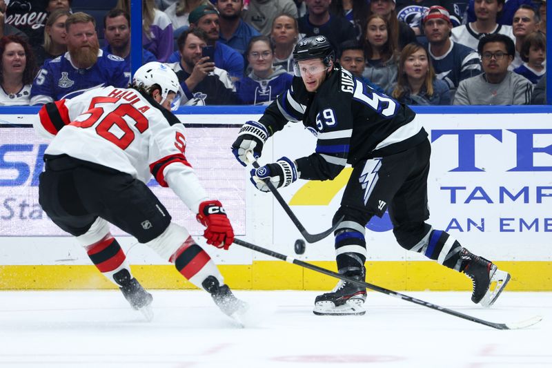Nov 16, 2024; Tampa, Florida, USA; Tampa Bay Lightning center Jake Guentzel (59) passes the puck past New Jersey Devils left wing Erik Haula (56) in the first period at Amalie Arena. Mandatory Credit: Nathan Ray Seebeck-Imagn Images