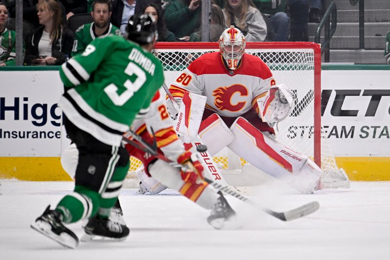 Mar 6, 2025; Dallas, Texas, USA; Calgary Flames goaltender Dan Vladar (80) faces a shot by Dallas Stars defenseman Matt Dumba (3) during the third period at the American Airlines Center. Mandatory Credit: Jerome Miron-Imagn Images