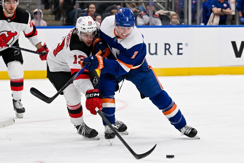 Mar 24, 2024; Elmont, New York, USA;  New York Islanders defenseman Mike Reilly (2) and away New Jersey Devils center Nico Hischier (13) battle for the puck during the first period at UBS Arena. Mandatory Credit: Dennis Schneidler-USA TODAY Sports