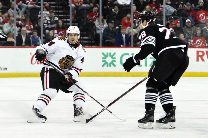 Dec 14, 2024; Newark, New Jersey, USA; Chicago Blackhawks defenseman Wyatt Kaiser (44) skates against New Jersey Devils right wing Timo Meier (28) during the first period at Prudential Center. Mandatory Credit: John Jones-Imagn Images