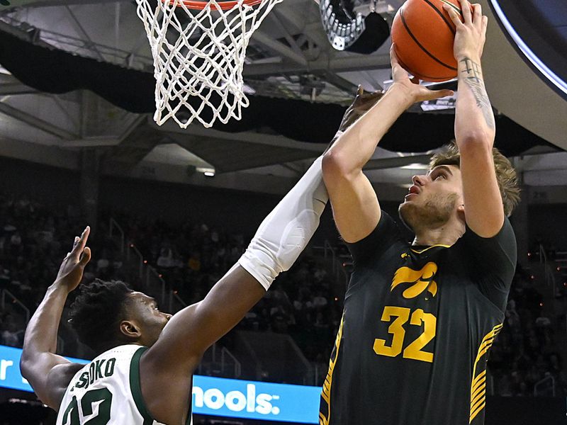 Feb 20, 2024; East Lansing, Michigan, USA;  Iowa Hawkeyes forward Owen Freeman (32) shoots past Michigan State Spartans center Mady Sissoko (22) during the first half at Jack Breslin Student Events Center. Mandatory Credit: Dale Young-USA TODAY Sports
