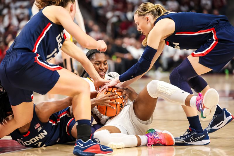 Feb 11, 2024; Columbia, South Carolina, USA; South Carolina Gamecocks guard Bree Hall (23) attempts to keep possession of the ball against  UConn Huskies guard Ashlynn Shade (12) and guard Paige Bueckers (5)  in the first half at Colonial Life Arena. Mandatory Credit: Jeff Blake-USA TODAY Sports