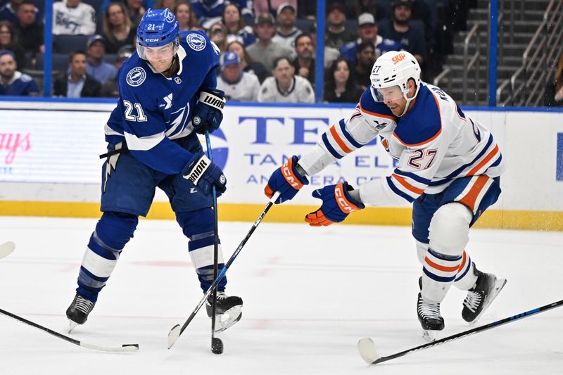 Feb 25, 2025; Tampa, Florida, USA; Tampa Bay Lightning center Brayden Point (21) and Edmonton Oilers defensemen Brett Kulak (27) attempt to gain control of the puck in the first period  at Amalie Arena. Mandatory Credit: Jonathan Dyer-Imagn Images