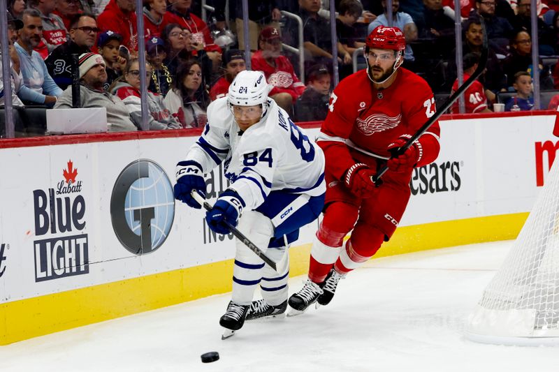 Oct 3, 2024; Detroit, Michigan, USA;  Toronto Maple Leafs defenseman Mikko Kokkonen (84) skates with the puck chased by Detroit Red Wings center Michael Rasmussen (27) in the second period at Little Caesars Arena. Mandatory Credit: Rick Osentoski-Imagn Images