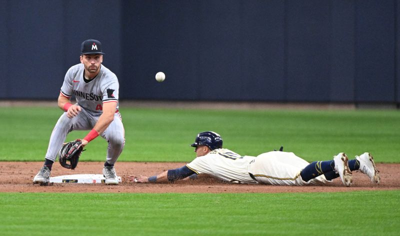 Apr 3, 2024; Milwaukee, Wisconsin, USA; Milwaukee Brewers center fielder Sal Frelick (10) slides safely into second base against Minnesota Twins second baseman Edouard Julien (47) in the second inning at American Family Field. Mandatory Credit: Michael McLoone-USA TODAY Sports