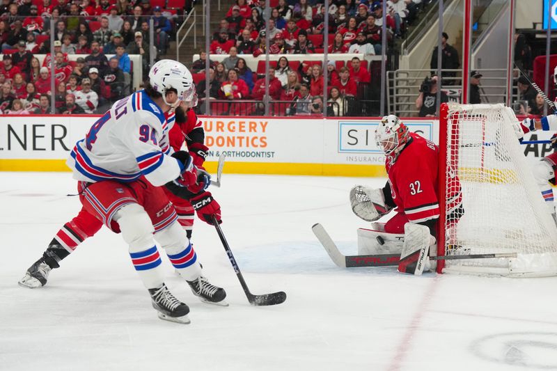 Dec 29, 2025; Raleigh, North Carolina, USA;  Carolina Hurricanes goaltender Brandon Bussi (32) stops the shot by New York Rangers right wing Gabe Perreault (94) during the second period at Lenovo Center. Mandatory Credit: James Guillory-Imagn Images