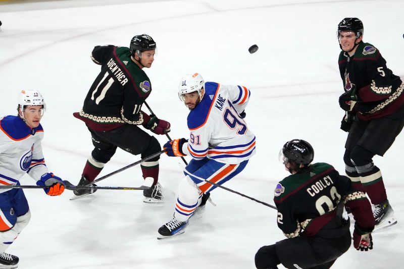 Feb 19, 2024; Tempe, Arizona, USA; Edmonton Oilers left wing Evander Kane (91) looks back at the puck while skating against Arizona Coyotes right wing Dylan Guenther (11) and Arizona Coyotes defenseman Michael Kesselring (5) during the third period at Mullett Arena. Mandatory Credit: Joe Camporeale-USA TODAY Sports