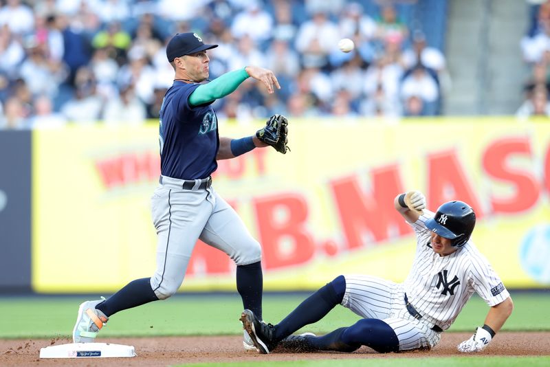 May 20, 2024; Bronx, New York, USA; Seattle Mariners shortstop Dylan Moore (25) forces out New York Yankees shortstop Anthony Volpe (11) at second base and throws to first on a fielder's choice by Yankees right fielder Juan Soto (not pictured) during the first inning at Yankee Stadium. Mandatory Credit: Brad Penner-USA TODAY Sports